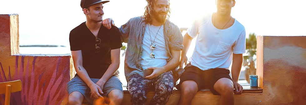 Three men sitting together on a bench with a warm, sunlit background
